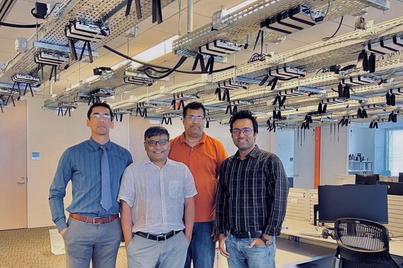 WiSig visitors tour testbed Four researchers standing in front of testbed